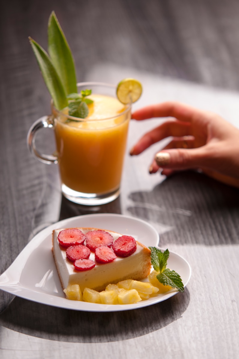 saucer of cake and cup of fruit juice on top of table